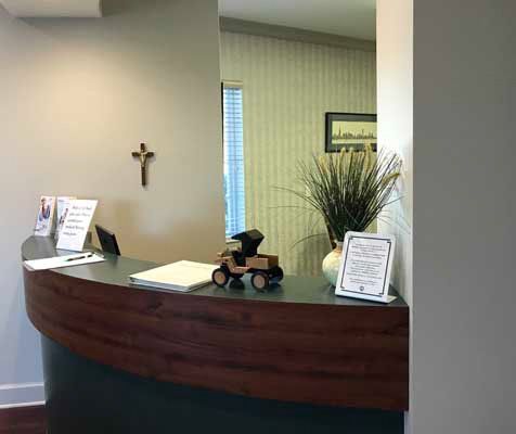 A reception desk in a dental office with a cross on the wall.
