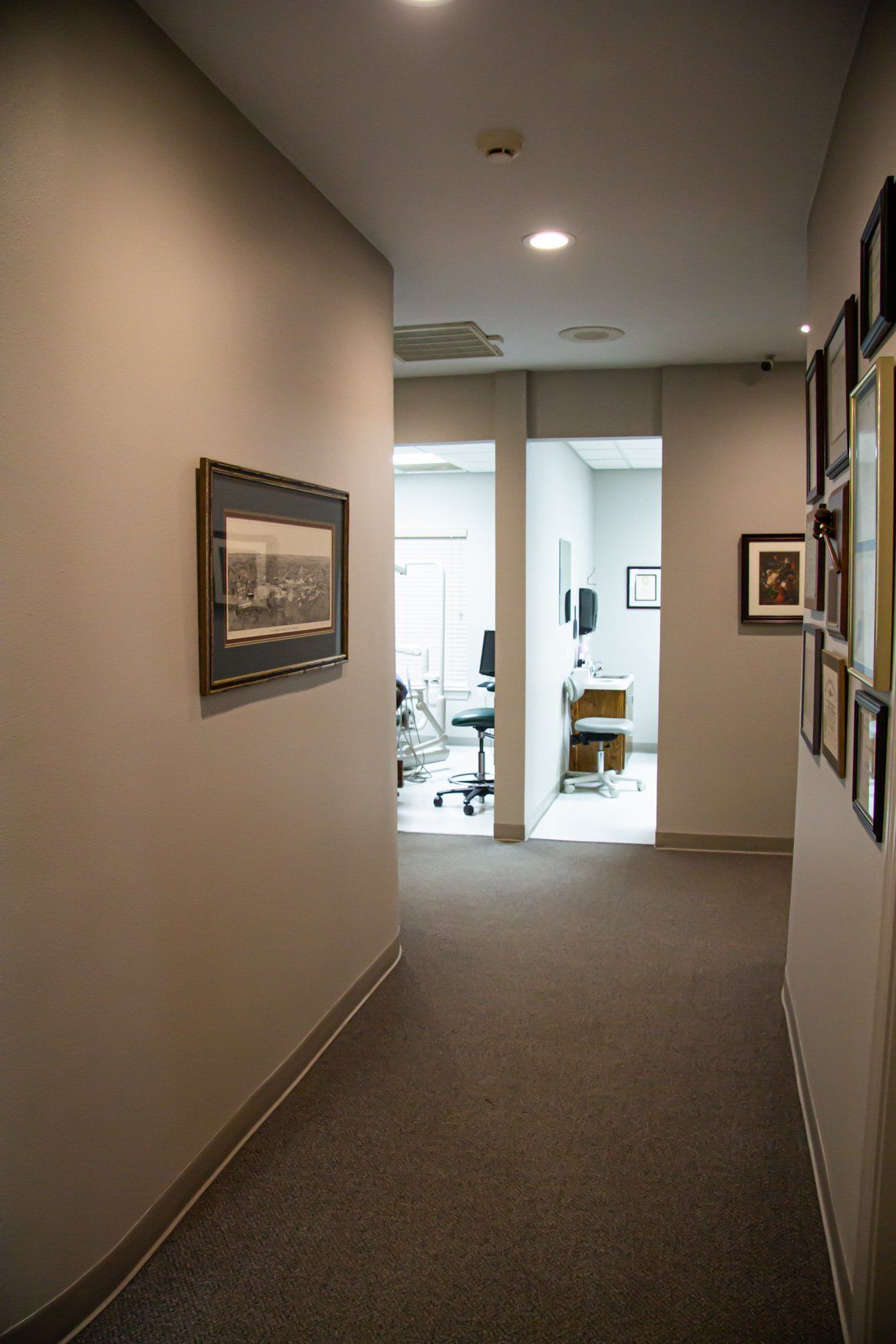 A long hallway leading to a dental office with a picture on the wall.