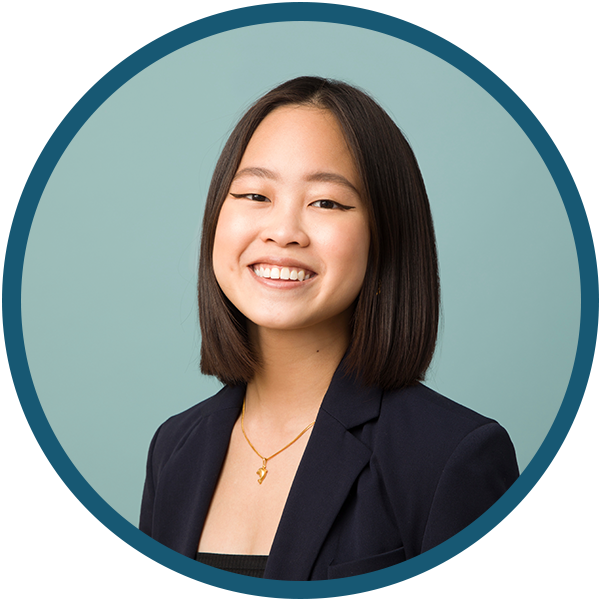 Portrait of a smiling person in a navy blazer against a light blue background, framed by a teal circle