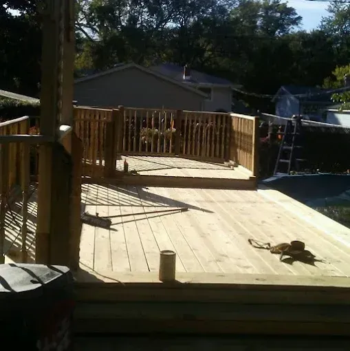 Wooden deck with railings being built outdoors. Sunny day.