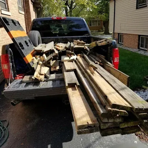 Truck bed overflowing with assorted wooden planks and boards.