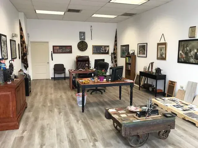 Office interior with desks, art, and antique cart on wood-look floor.