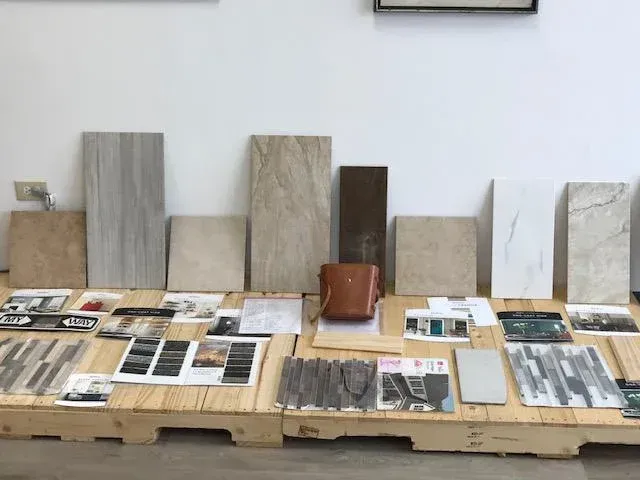 Samples of tile displayed on a wooden pallet, with a purse in the center. White wall in background.