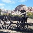 Old wooden wagon with mountain backdrop on a sunny day.