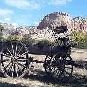 Old wooden wagon with mountain backdrop on a sunny day.