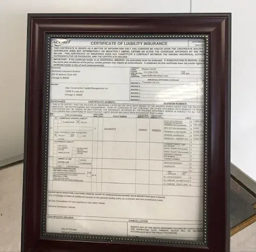 Framed certificate of insurance with a maroon wooden frame.