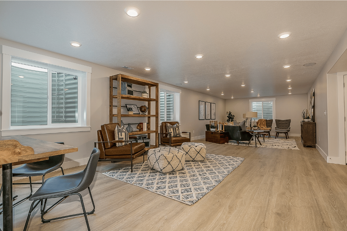 Spacious finished basement with seating areas, a dining table, and large windows.