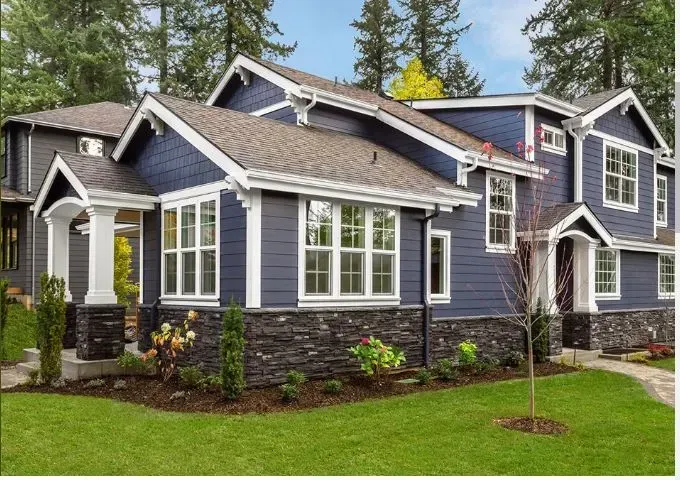 Blue house with white trim, black stone accents, and a green lawn.