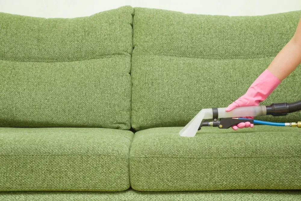 Hand in Pink Glove Using a Cleaning Tool on a Green Sofa — Phil Lindfield's Big Red Carpet Cleaning In Taree, NSW