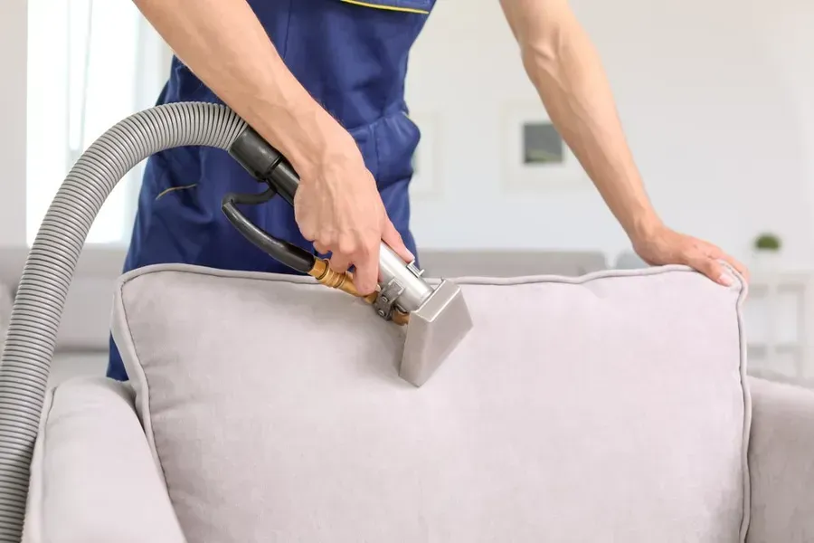 Person Cleaning Light Gray Upholstered Chair With a Vacuum — Phil Lindfield's Big Red Carpet Cleaning In Hallidays Point, NSW