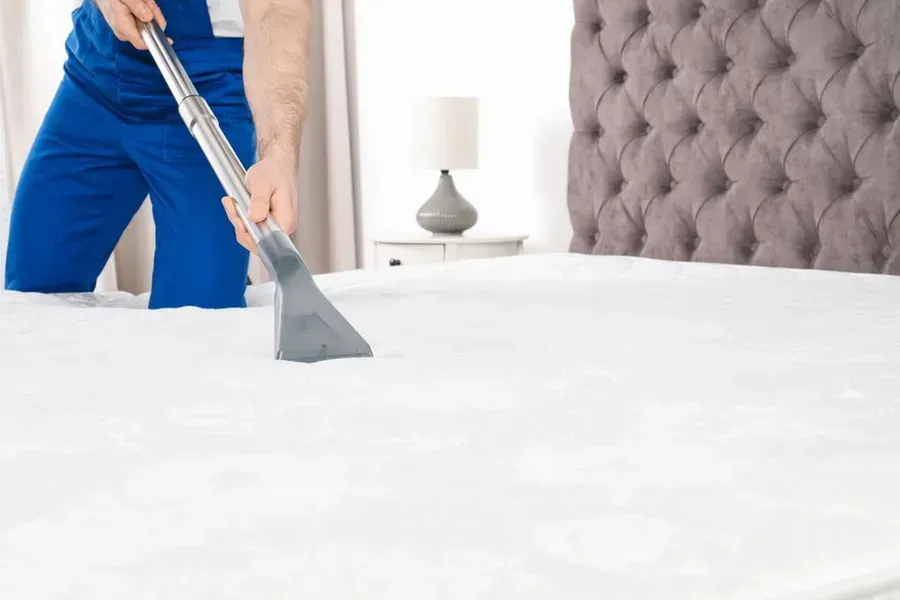 Person in Blue Cleaning a White Mattress — Phil Lindfield's Big Red Carpet Cleaning In Tuncurry, NSW