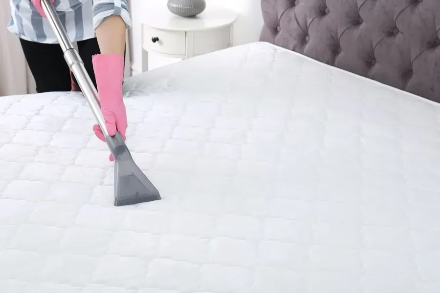 Person in Pink Gloves Vacuuming a White Quilted Mattress — Phil Lindfield's Big Red Carpet Cleaning In Diamond Beach, NSW