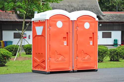 Two orange color portable toilet in the park
