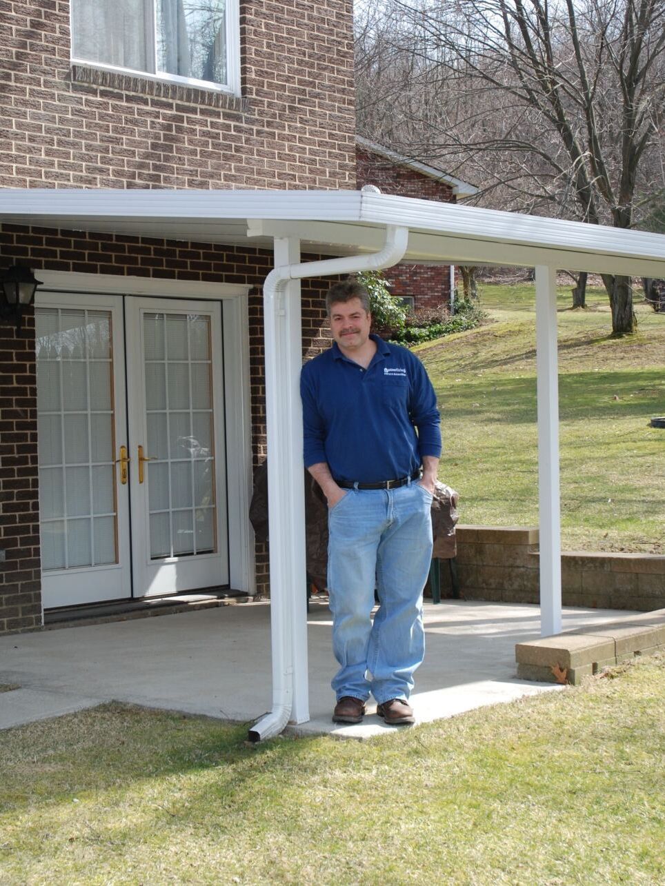 A man in a blue shirt is standing on a porch