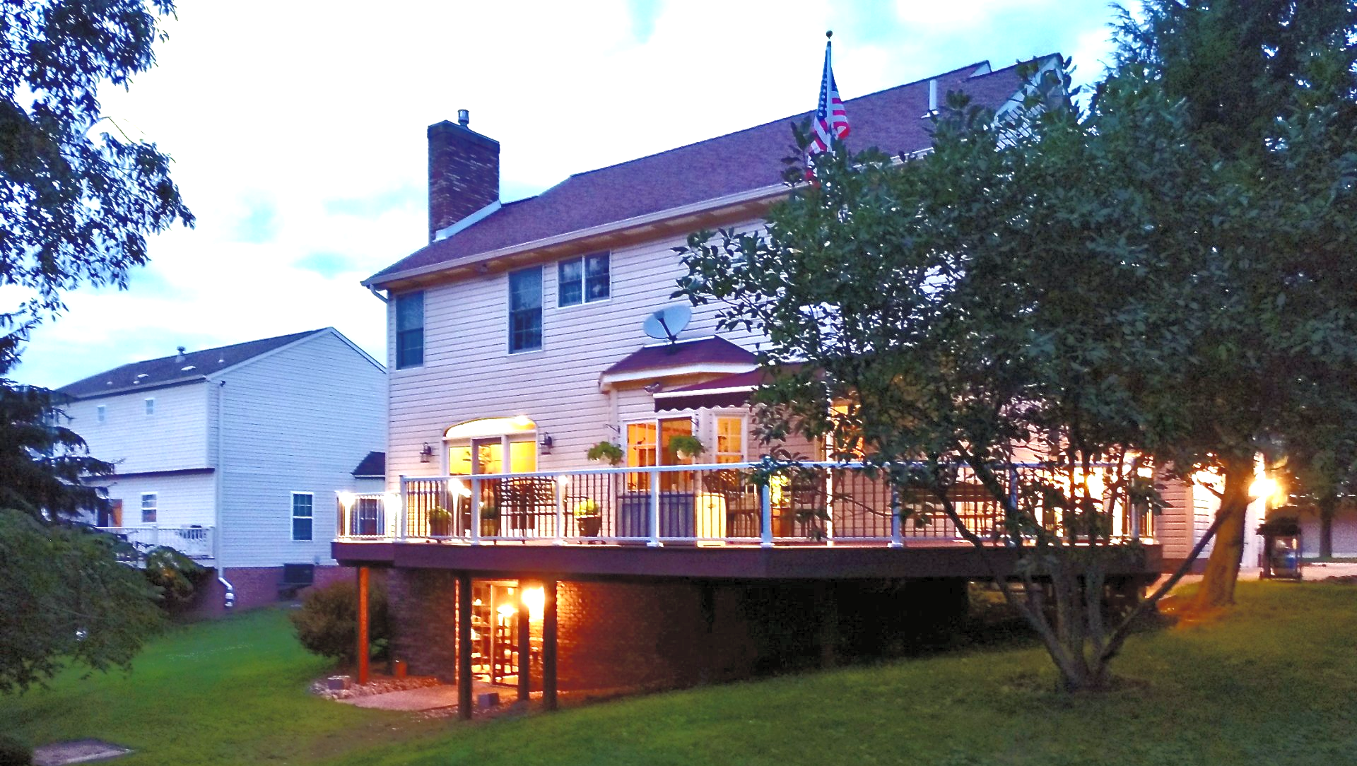 A house with a large deck is lit up at night