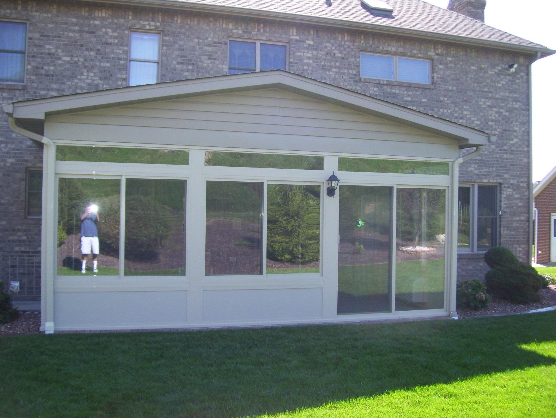 A man is standing in front of a screened in porch