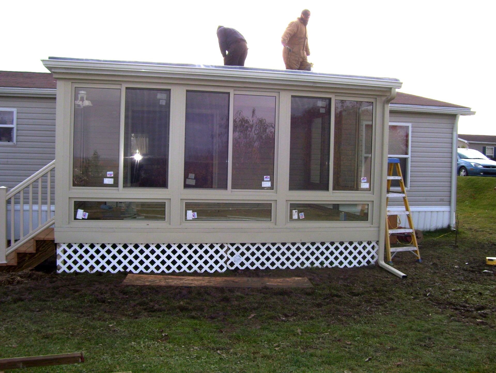 A man is standing on the roof of a screened in porch