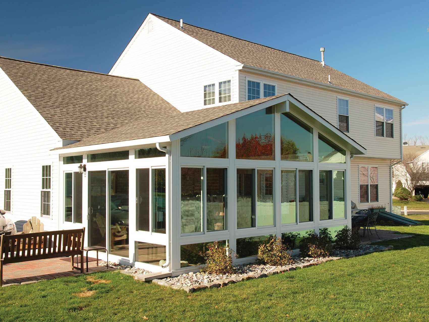 A large white house with a sunroom in the backyard