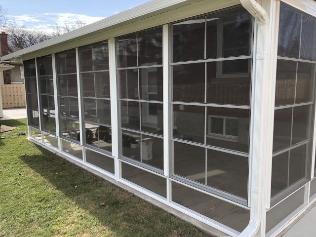 a screened in porch with lots of windows on the side of a house .
