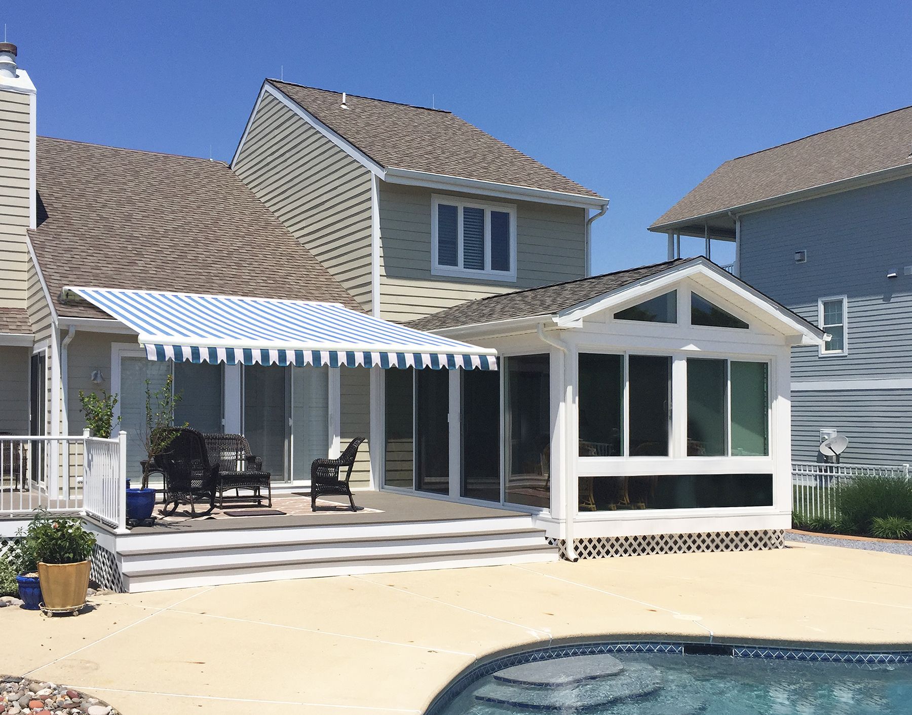A house with a swimming pool and a blue and white awning