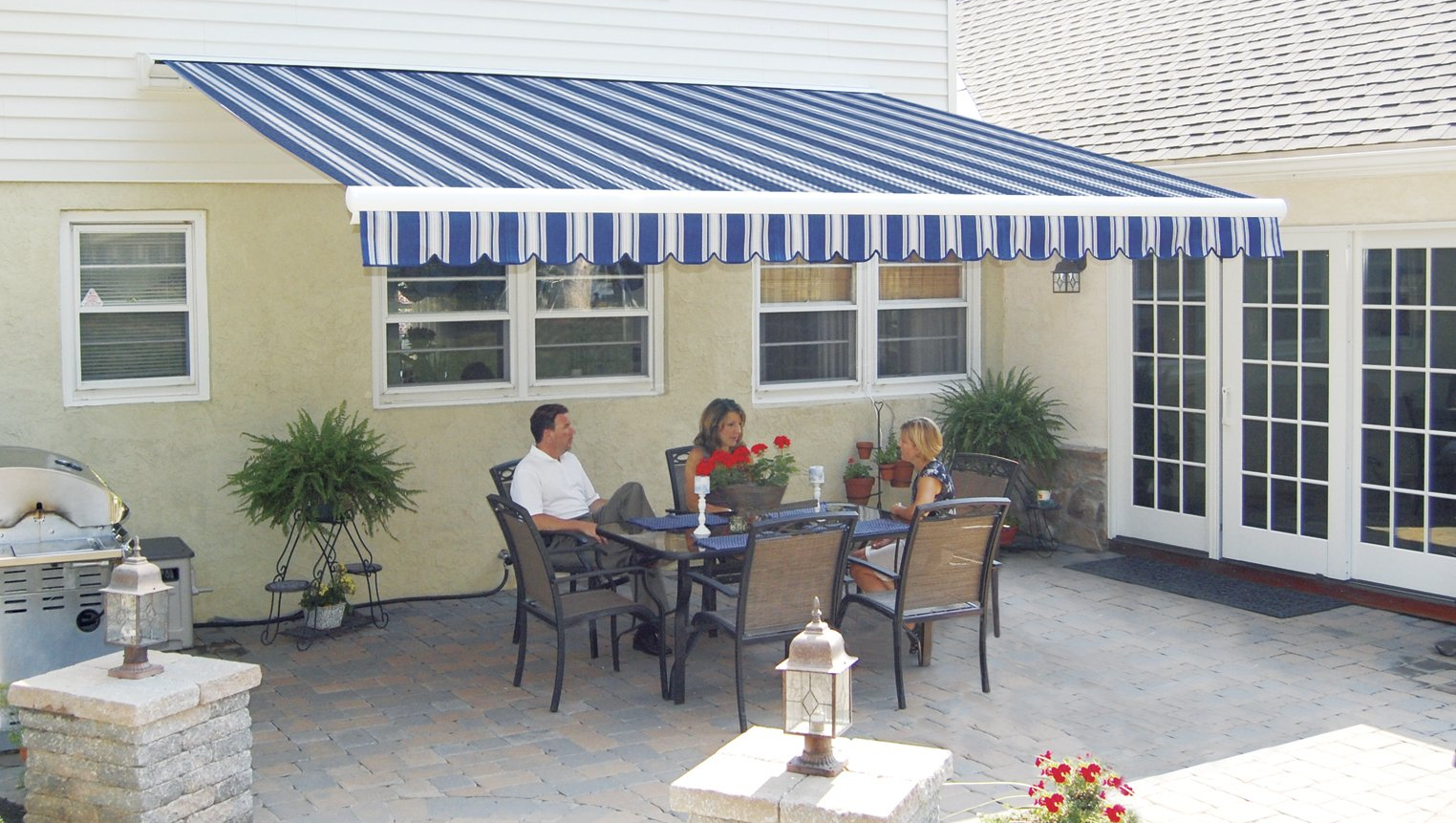 A family sits at a table under a blue and white awning