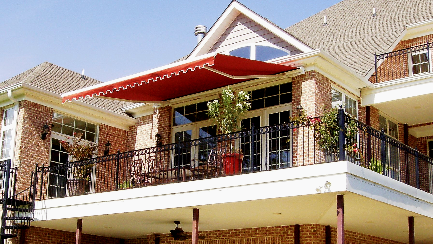 A large brick house with a balcony with a red awning