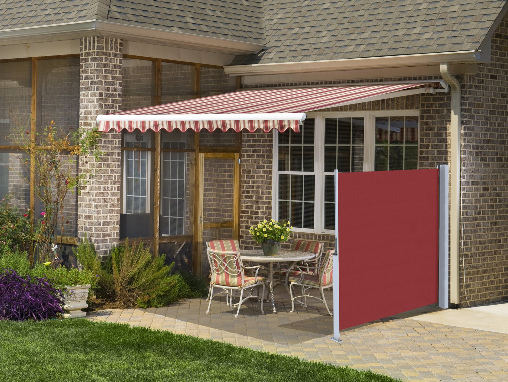 A brick house with a red and white awning over a patio