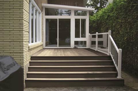 A wooden deck with stairs leading up to it and a white railing.