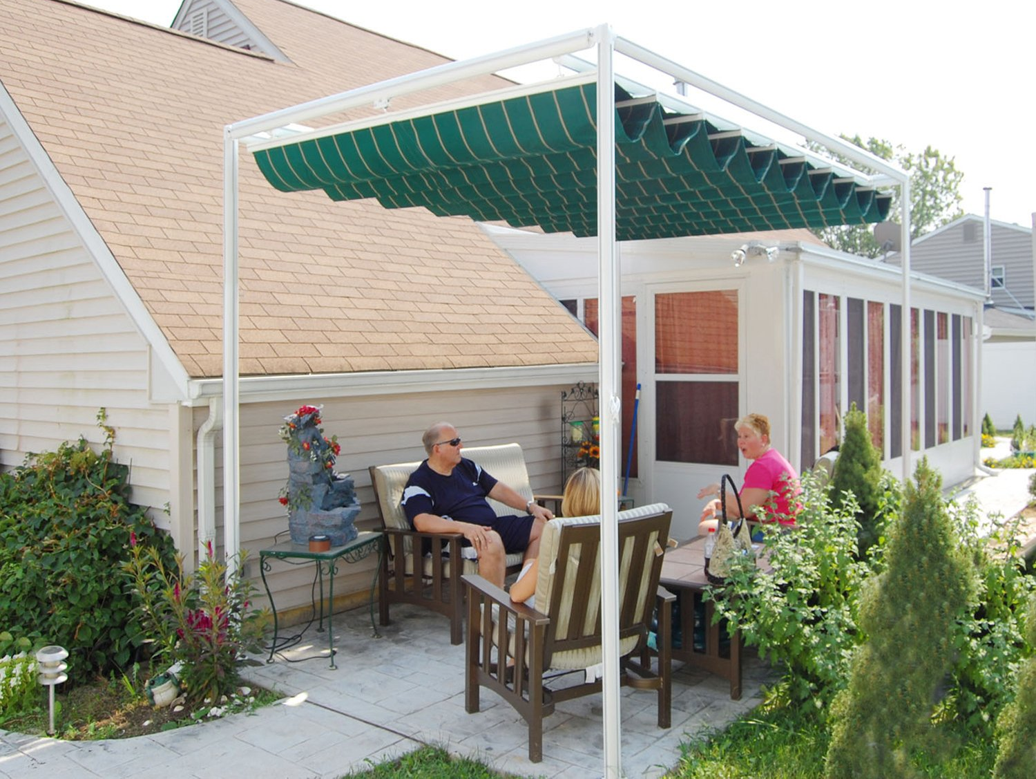 A man and woman sit under a green awning on a patio