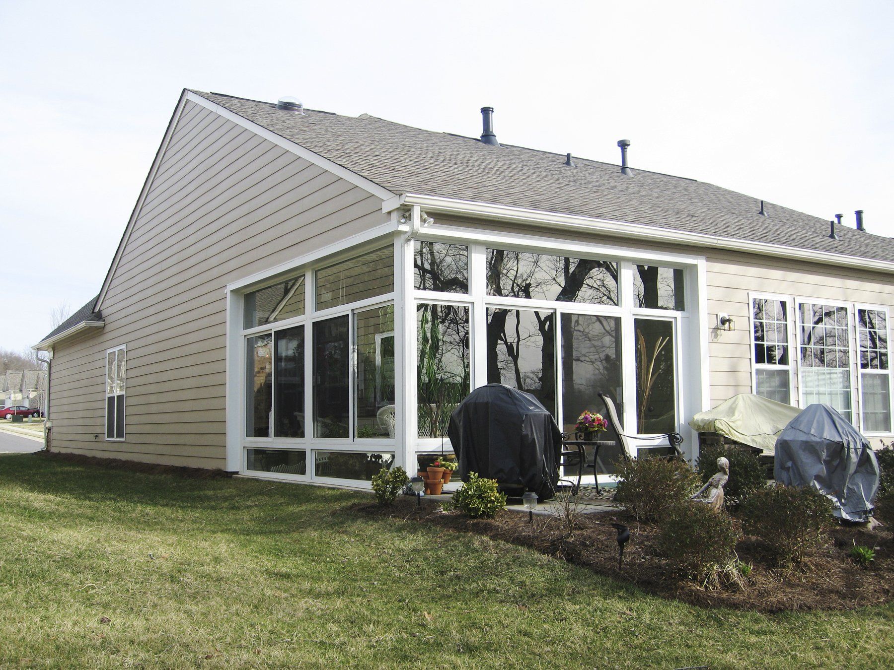 A house with a screened in porch and a grill