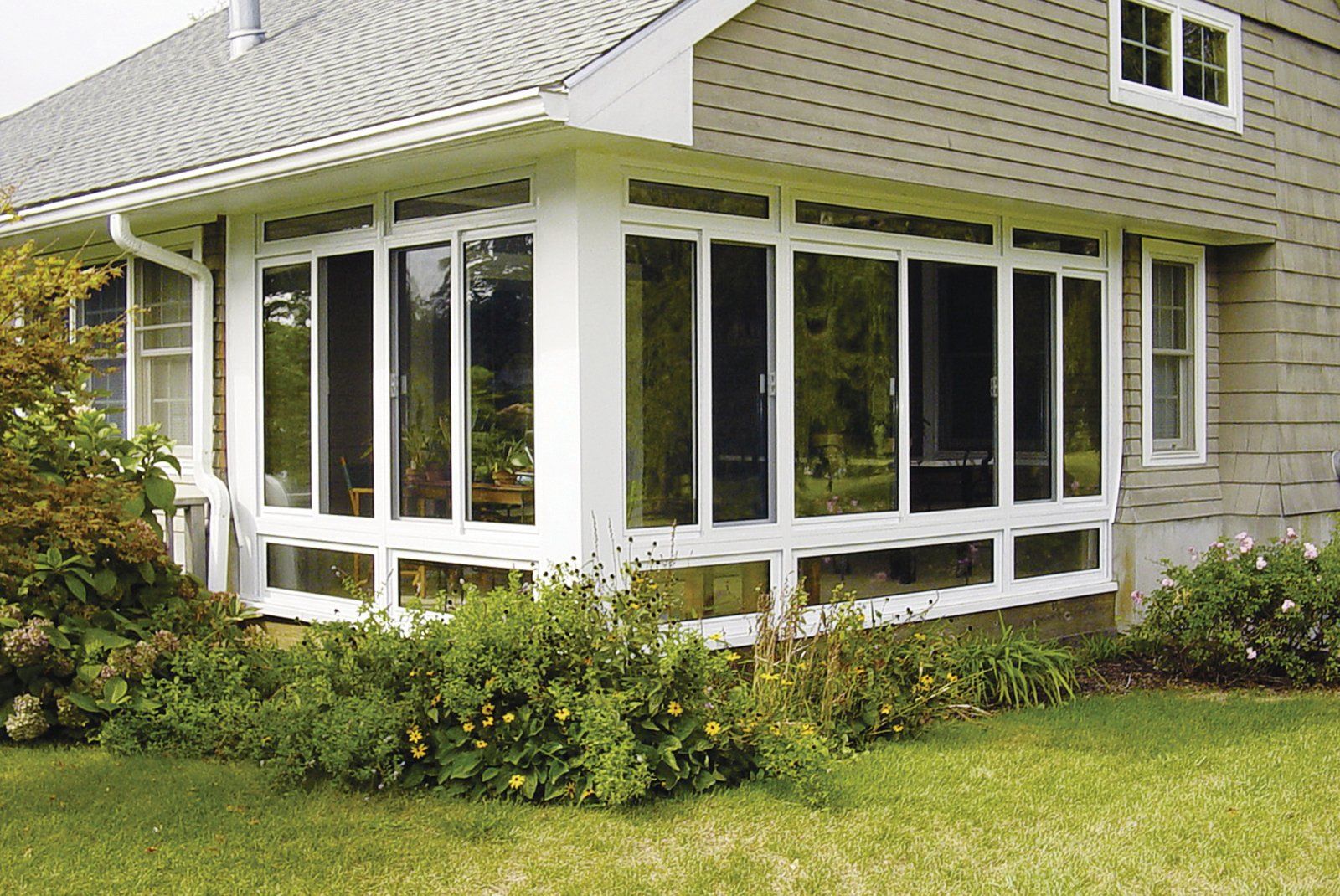 A house with a screened in porch and lots of windows