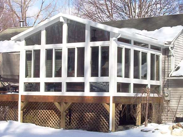 A white sunroom with a lot of windows is in the snow