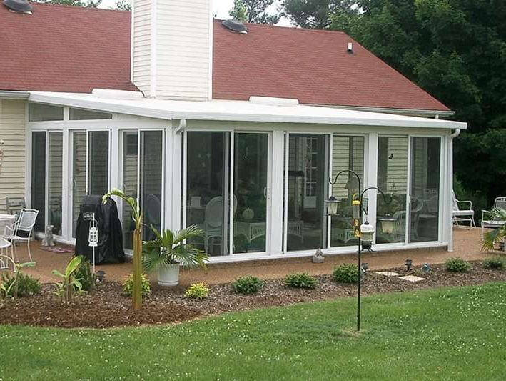 A white house with a red roof and a sunroom
