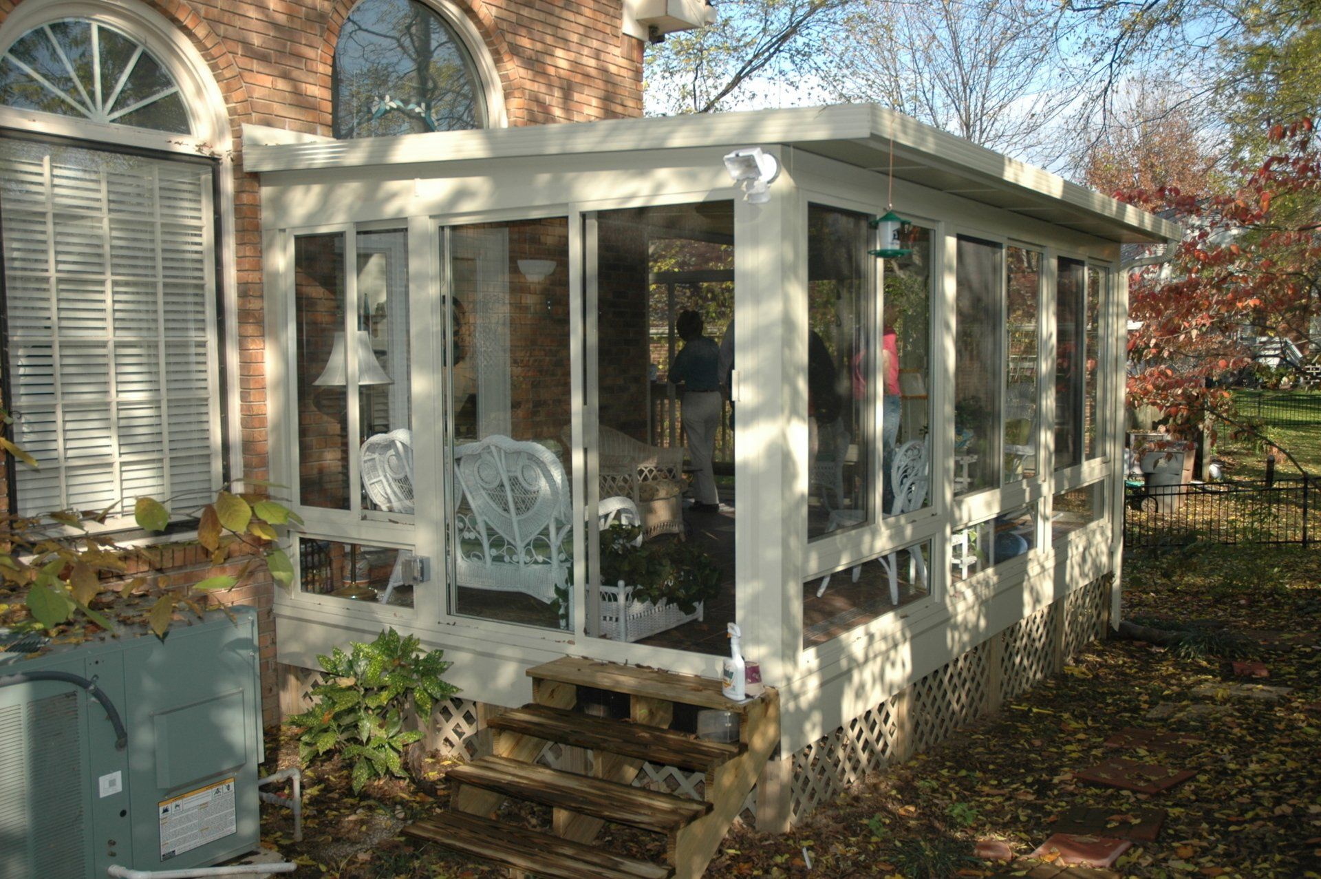 A screened in porch with a brick building in the background
