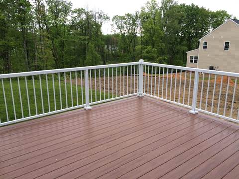 A wooden deck with a white railing and a house in the background.