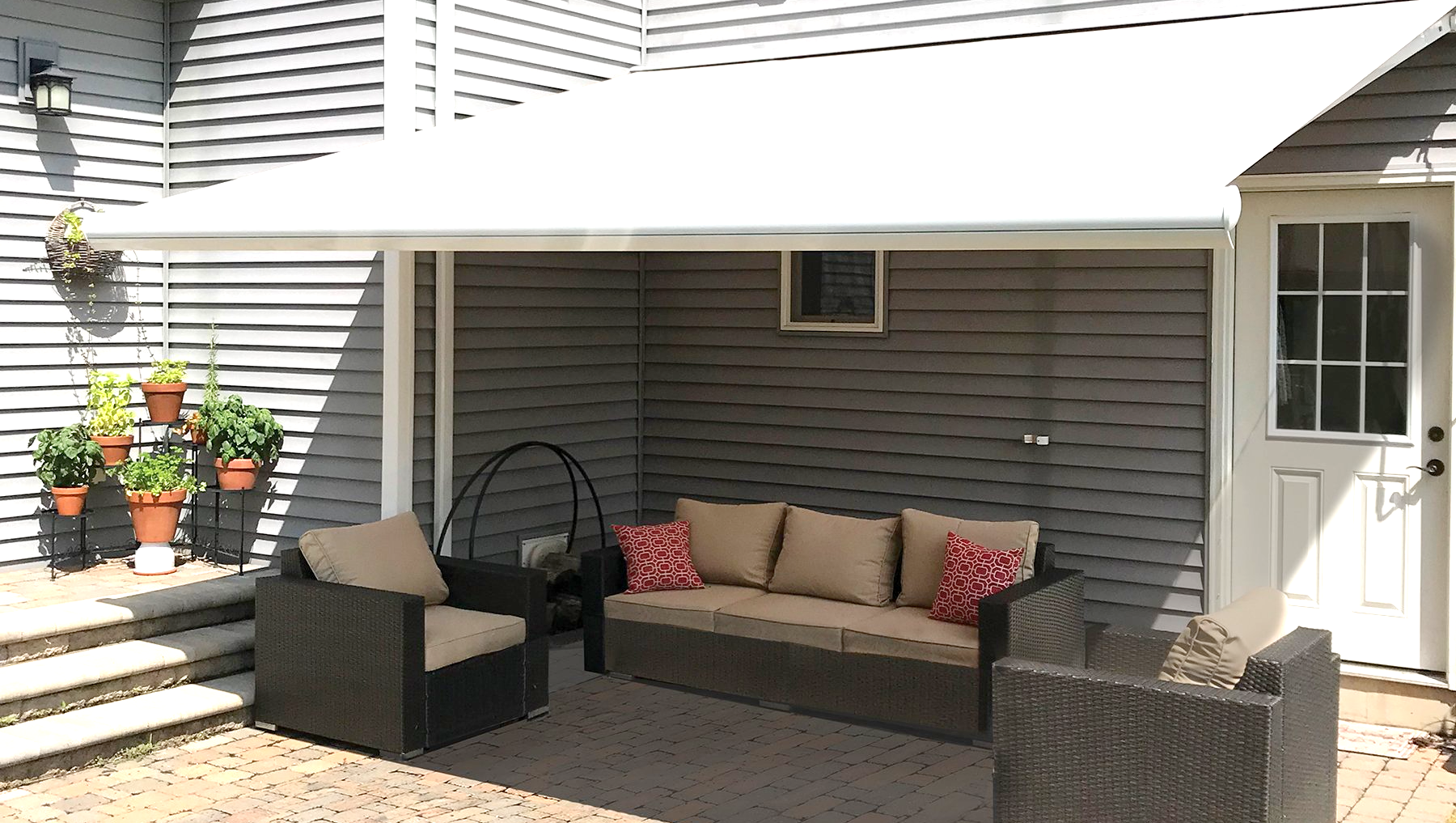 A patio with a couch and chairs under a white awning