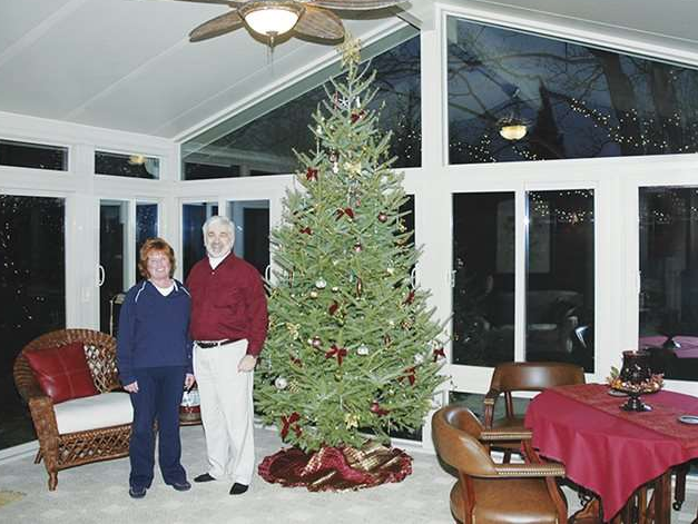 A man and woman standing in front of a christmas tree