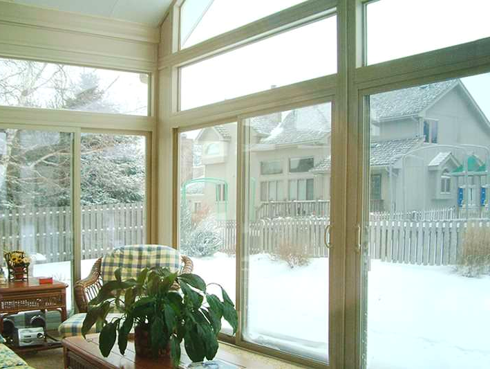 A living room with a lot of windows and a plant on the table