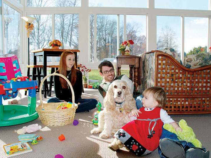 A family is playing with a dog in a sunroom
