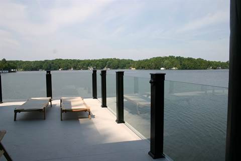 A dock with a glass railing overlooking a lake.