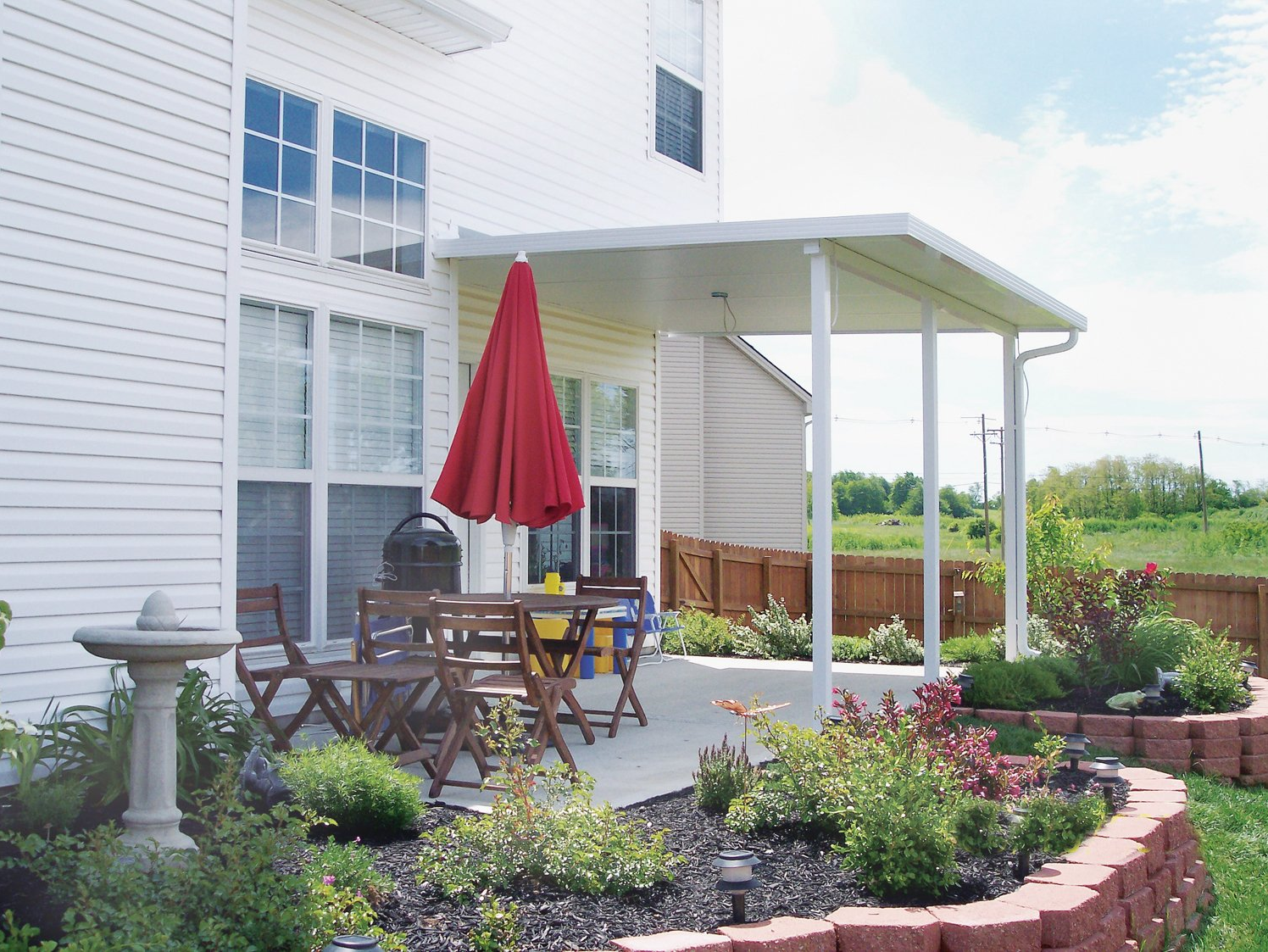 A patio with a red umbrella and a table and chairs