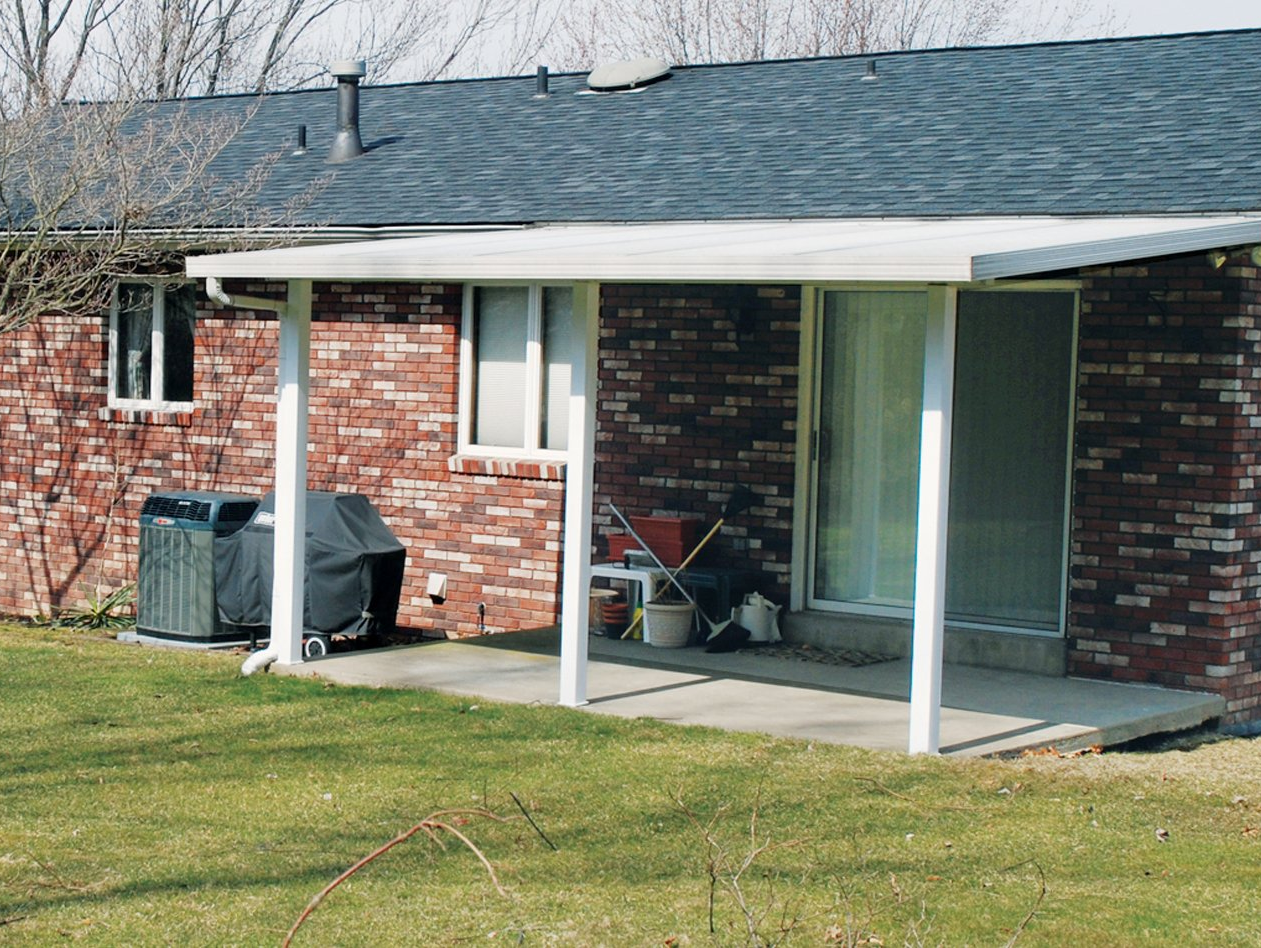 A brick house with a white porch and a black roof