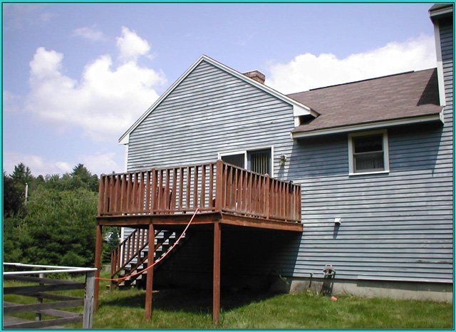 A blue house with a wooden deck and stairs