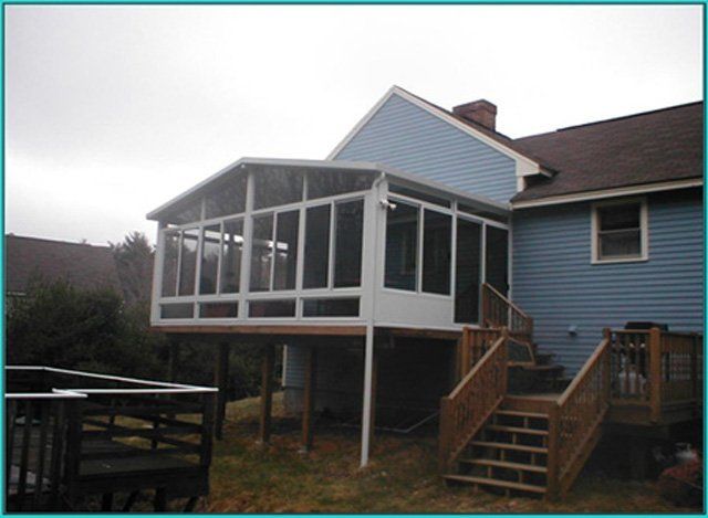 A blue house with a screened in porch and stairs