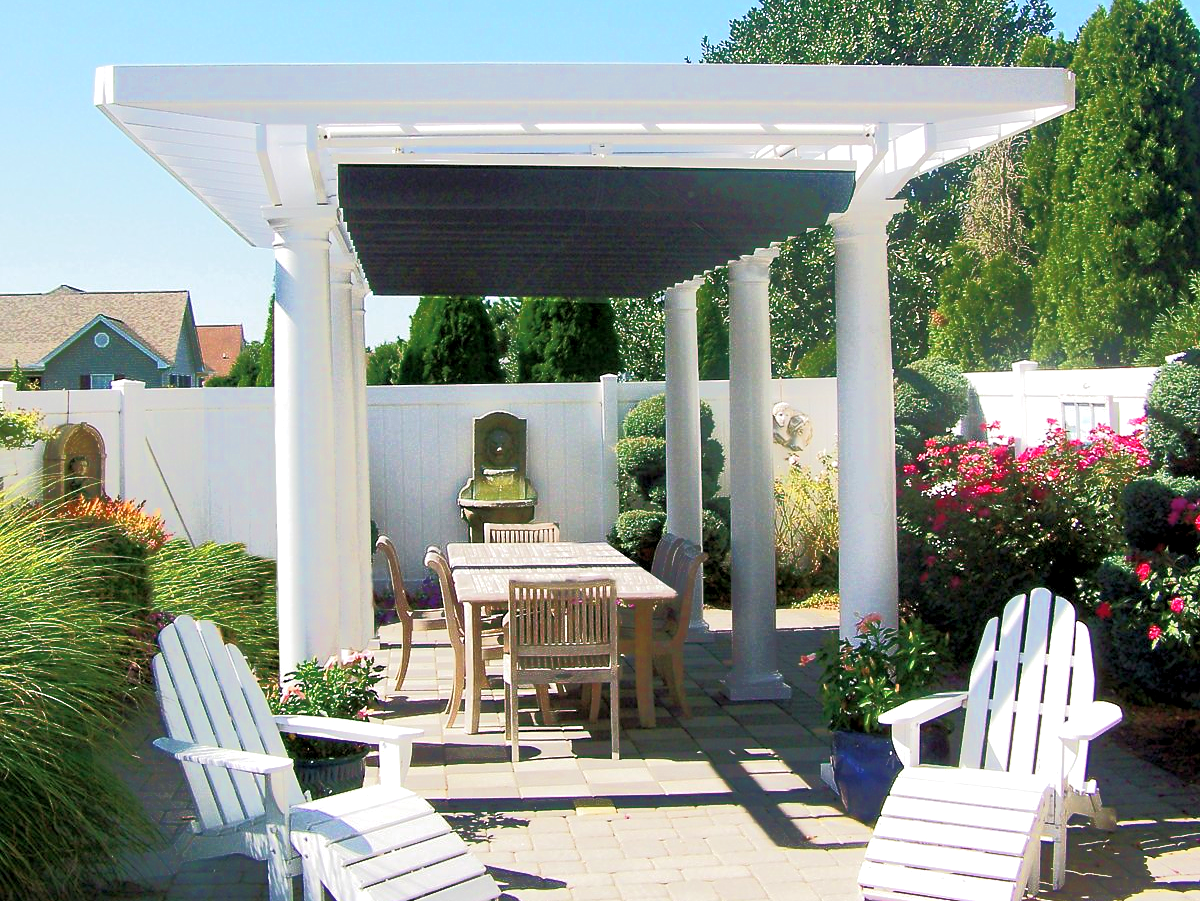 A white pergola with a table and chairs underneath it