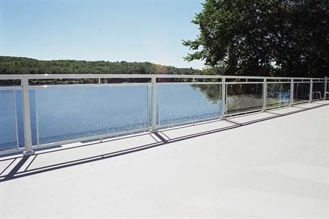 A bridge with a glass railing overlooking a lake