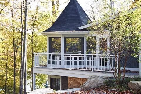 A gazebo with a black roof is surrounded by trees.
