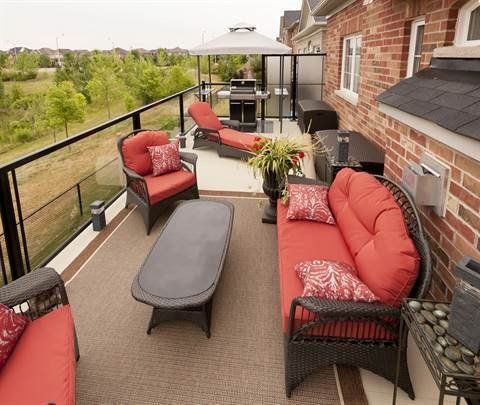 A balcony with a couch , chairs , table and umbrella.