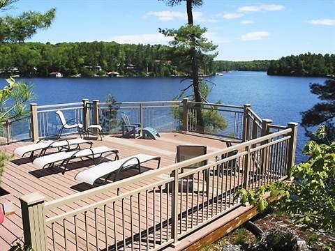 A deck overlooking a lake with lounge chairs on it