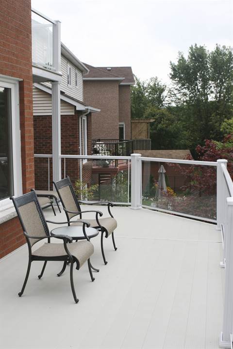 A deck with chairs and a table in front of a brick house